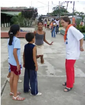 Fotografía de una maestra con estudiantes en el patio de la escuela, conversando.