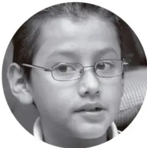 Fotografía en blanco y negro de un niño con lentes que mira a la cámara.
