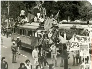 Fotografía de una marcha con pancartas que dicen 'CONTRA LA REPRESIÓN' y 'LA PRESENTACIÓN DE LOS DESAPARECIDOS POLÍTICOS'.