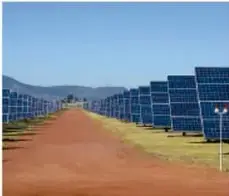Campo de paneles solares alineados sobre una superficie rojiza.