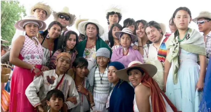 Fotografía de un grupo comunitario diverso (mujeres, hombres, niñas y niños) con vestimenta y sombreros tradicionales, representando la diversidad y el sentido de pertenencia comunitario.