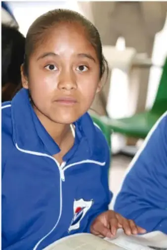 Fotografía de una estudiante de secundaria con uniforme azul, sentada en el aula, que ilustra el trabajo individual y en comunidad de la actividad.