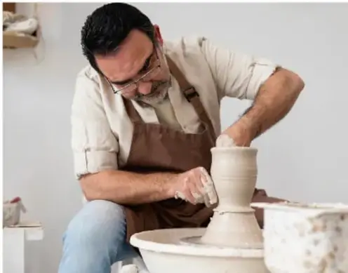Fotografía de un artesano alfarero trabajando una pieza de cerámica en su torno, representando la producción artesanal.