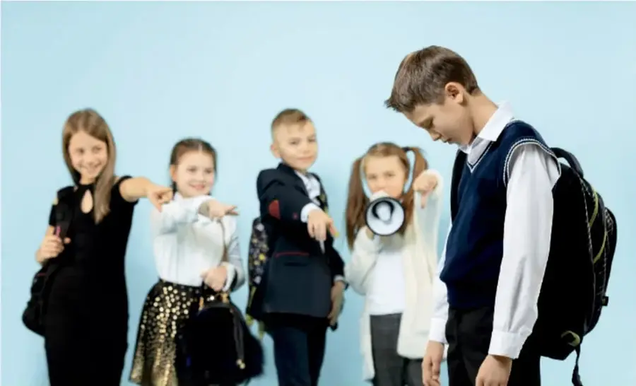 Cinco estudiantes de primaria con uniforme escolar; uno sostiene un megáfono y otro lleva mochila, representando la organización y convocatoria de talleres.