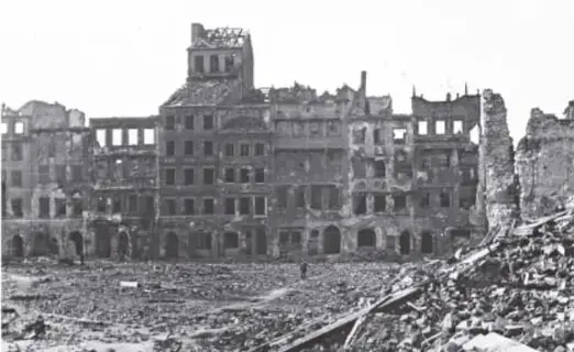 Fotografía en blanco y negro de una ciudad europea devastada por la guerra, con edificios en ruinas y escombros.