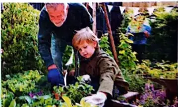 Una persona adulta y un niño cultivan alimentos, como ejemplo de permacultura.