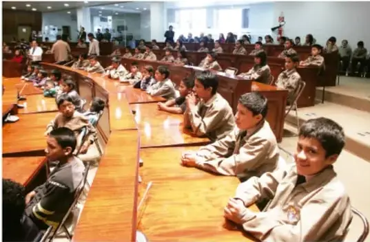 Estudiantes de primaria sentados en mesas de madera dentro de un aula, participando en una actividad grupal.