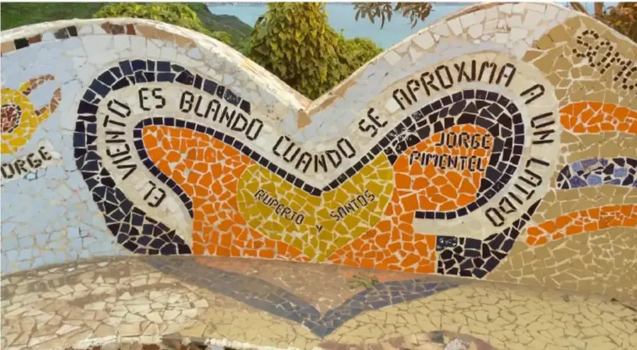 Fotografía de un mosaico de trencadís con el verso "El viento es blando cuando se aproxima a un lirio", firmado por Jorge Pimentel y realizado por Rupert y Santos.
