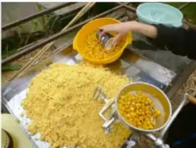 Fotografía de masa de maíz molida (nixtamal) sobre una superficie con un utensilio de molido.