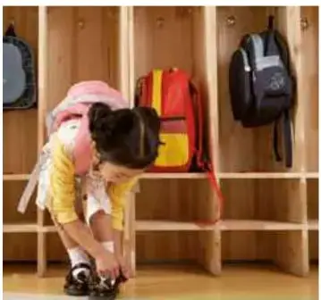 Niña de espaldas guardando una mochila roja en un casillero de madera con varias mochilas colgadas.