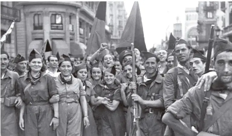 Fotografía en blanco y negro de un grupo de milicianos, hombres y mujeres, con uniformes y armas, marchando por una calle.