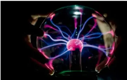 Esfera de plasma con descargas eléctricas de colores rosa, azul y violeta, que ilustra la relación entre magnetismo y energía eléctrica.