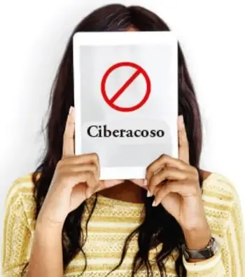 Fotografía de una persona sosteniendo una hoja con un símbolo de prohibición y la palabra 'Ciberacoso'.