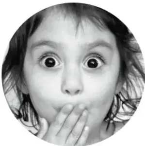 Fotografía circular en blanco y negro de una niña sorprendida, con los ojos muy abiertos y la mano en la boca.