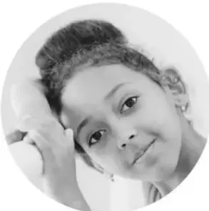 Fotografía circular en blanco y negro de una niña sonriente con la mano en la mejilla.