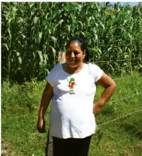 Mujer junto a un sembradío de maíz, encuadre de tres cuartos, plano americano.