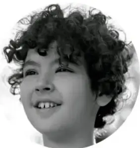 Retrato en blanco y negro de un niño sonriente con cabello rizado.