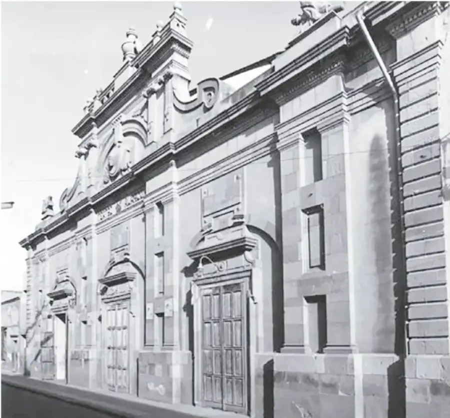 Fotografía en blanco y negro de la fachada del Teatro Alarcón: edificio de cantera con portadas de arcos, grandes puertas de madera y adornos barrocos en la parte superior.