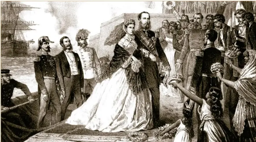 Litografía de 1864 de V. H. Gerhart que muestra la llegada del emperador Maximiliano y la emperatriz Carlota al puerto de Veracruz: la pareja aparece en el centro recibiendo flores de una multitud, con barcos y banderas al fondo, en un ambiente celebratorio.