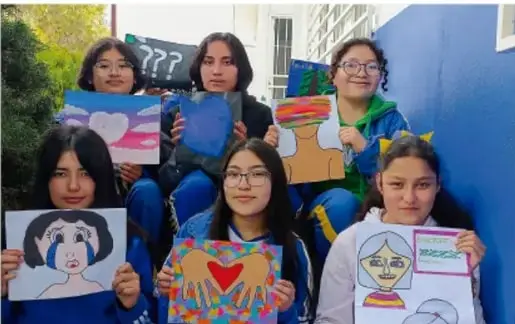 Fotografía de estudiantes mostrando trabajos artísticos con dibujos de rostros y corazones. Crédito: Luis Eduardo García Medel, TLAXCALA.