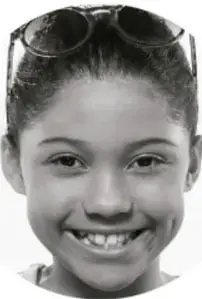 Fotografía de una niña sonriente con lentes sobre la cabeza.