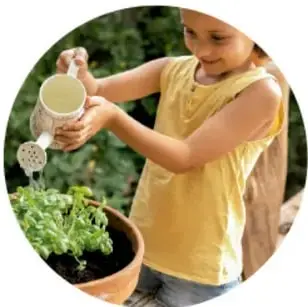 Niña regando una planta con una regadera.