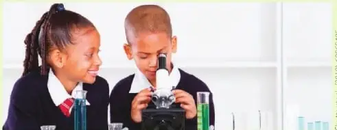 Dos estudiantes observan una muestra con un microscopio durante una actividad experimental.