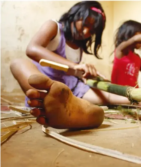 Niña trabajando con fibra vegetal, imagen relacionada con trabajo infantil o forzado.