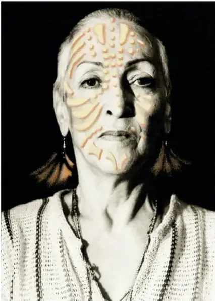 Retrato en blanco y negro de una mujer anciana con marcas faciales (escarificaciones o pinturas) en la frente y mejillas.
