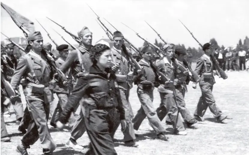 Fotografía en blanco y negro de soldados en formación marchando con fusiles al hombro y banderas, probablemente del bando republicano o de las Brigadas Internacionales durante la Guerra Civil Española.