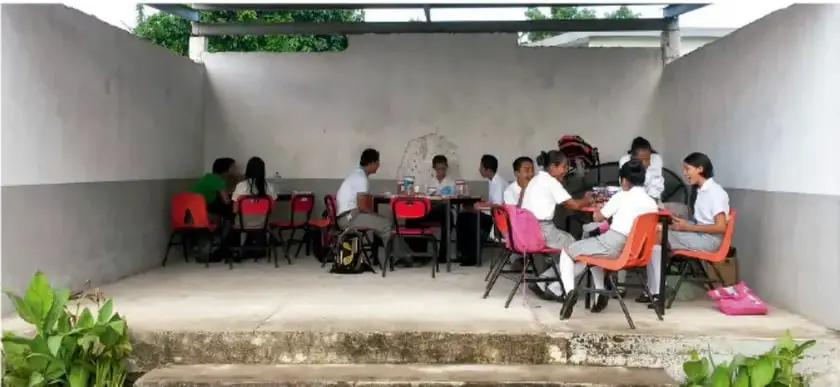 Fotografía de estudiantes de Telesecundaria trabajando en equipo al aire libre en mesas, realizando actividades del proyecto.