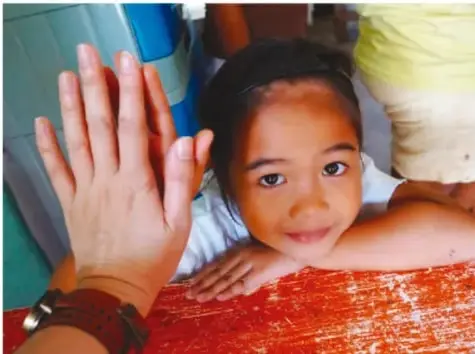 Fotografía de cuatro niños mostrando sus palmas abiertas hacia adelante, comparando el tamaño de sus manos.