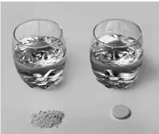 Fotografía de dos vasos transparentes con agua, media pastilla efervescente y un montón de polvo obtenido al moler la otra pastilla.