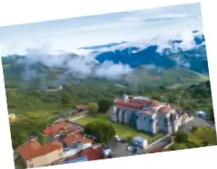 Paisaje de montañas con nubes y casas al pie.