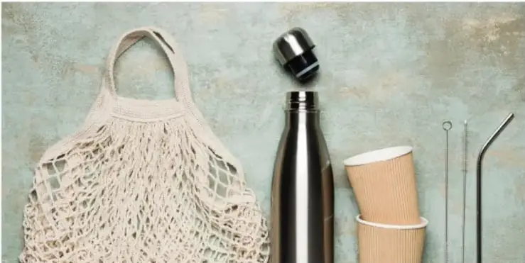 Objetos de consumo sostenible: bolsa de red reutilizable, botella térmica de acero, vasos de cartón y popotes metálicos.