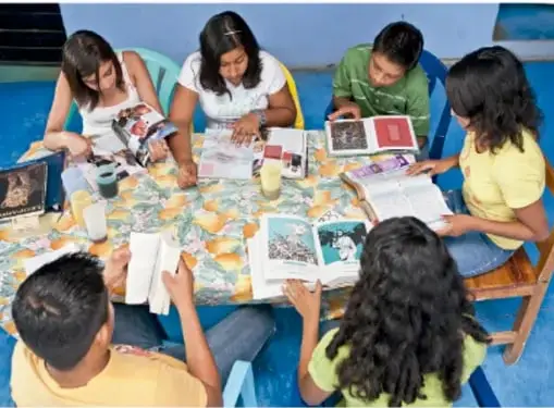 Fotografía de estudiantes reunidos alrededor de una mesa revisando libros y revistas; crédito: Francisco Manuel Palma Lagunas, Ciudad de México.