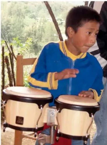 Niño tocando dos tambores o congas al aire libre.