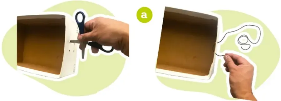 Manos usando tijeras para perforar el centro de una cara de la caja de zapatos.