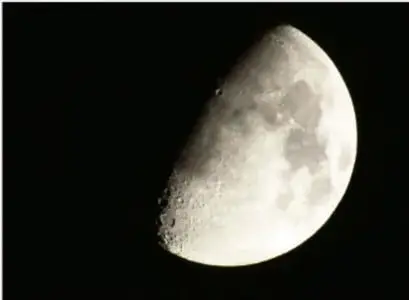 Fotografía de la Luna en fase de cuarto (mitad iluminada) sobre fondo negro.