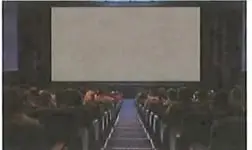 Fotografía de una sala de cine con butacas orientadas hacia una pantalla.