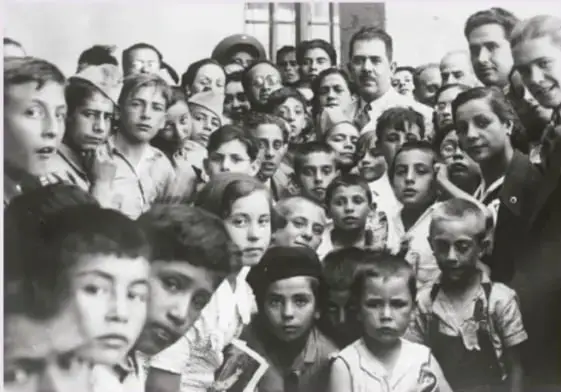 Fotografía en blanco y negro de un grupo numeroso de niños y niñas españoles refugiados, conocidos como los niños de Morelia, acompañados por algunos adultos.