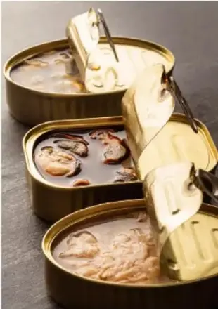 Fotografía de tres latas de conservas (sardinas o pescado) abiertas, ejemplo de alimentos envasados al vacío.