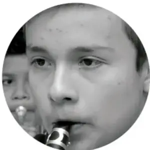 Fotografía en blanco y negro de un niño tocando un instrumento de viento.