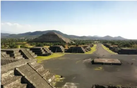 El Castillo de Chichén Itzá con una gran cabeza de serpiente emplumada de piedra en primer plano, bajo cielo azul.