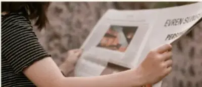 Persona leyendo un periódico con las piernas cruzadas.