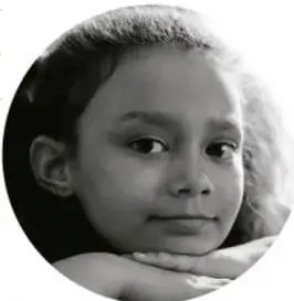 Fotografía en blanco y negro de una niña con la barbilla apoyada en las manos, mirando al frente.
