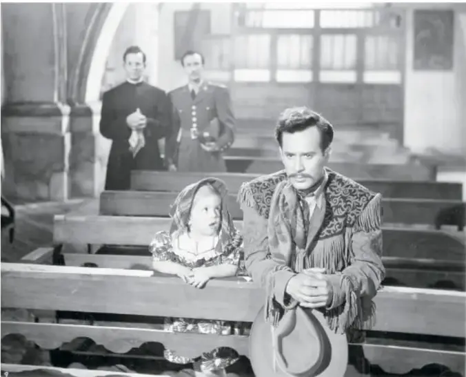 Fotografía en blanco y negro de Pedro Infante en traje de charro dentro de una iglesia, junto a una joven arrodillada.