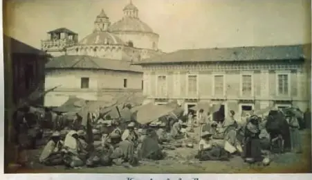 Fotografía histórica de comerciantes indígenas en la Plaza de San Francisco de Quito, entre 1885 y 1895. Se observan personas comercializando productos en el mercado.