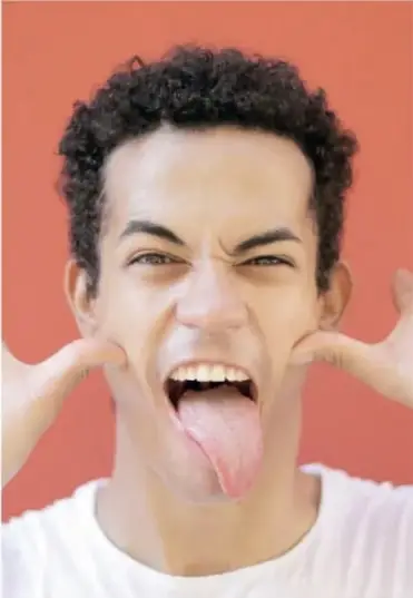 Fotografía completa del joven haciendo gestos con las manos y la lengua.