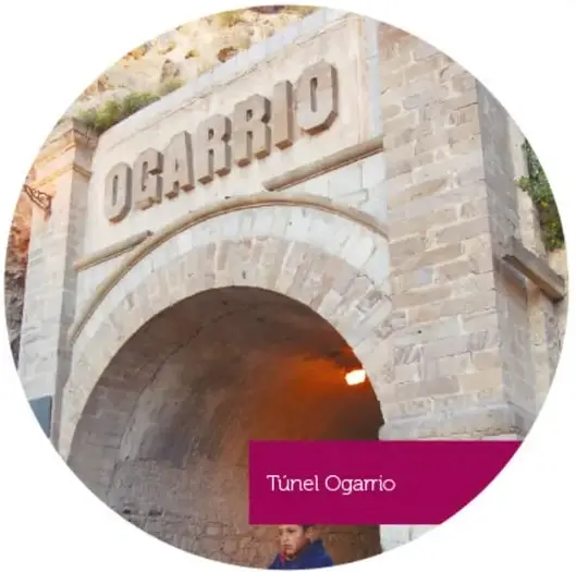 Túnel Ogarrio: entrada de arco de piedra con la palabra Ogarrio grabada y luz anaranjada al fondo.